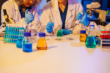 middle-aged man, an old woman, and a young woman collaborate in a lab at night, under blue and RGB lighting, researching food ingredients and conducting experiments with test tubes and microscopes.