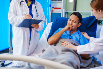 A middle-aged man lies bedridden on hospital bed, closely monitored by an old Asian woman doctor...