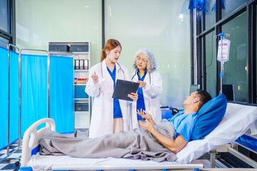 A middle-aged man lies bedridden on hospital bed, closely monitored by an old Asian woman doctor...