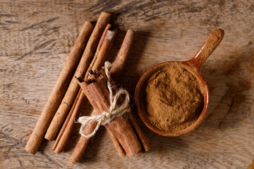 Aromatic cinnamon sticks and powder on wooden table.