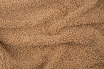 Soft, textured fabric draped elegantly on a surface in warm, neutral tones during daylight