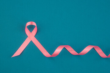 Pink ribbon symbolizing breast cancer awareness on a turquoise background during October campaign