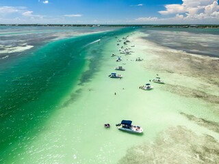 Motor boats moored in shallow tropical water and sunbathing people in Whale Harbor Channel, Wilson Key, Florida, United States.