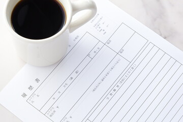 コーヒーを飲みながら、履歴書を書く
