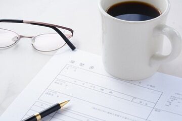 コーヒーを飲みながら、履歴書を書く
