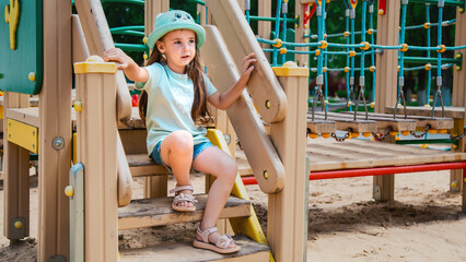 The child plays in the outdoor playground. Children play in the courtyard of a school or kindergarten. Healthy summer fun for kids.