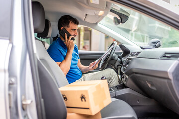 Courier talking to the mobile inside a van with packages © unai
