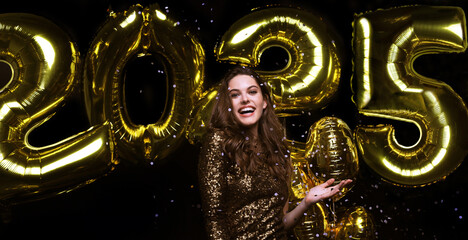 Happy gorgeous girl in stylish sexy party dress holding gold 2025 balloons, having fun at New Year's Eve Party.
