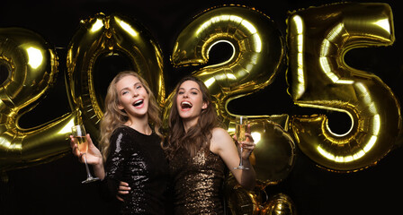 Two young ladies drinking champagne. Image of girls with balloons isolated on black background,...