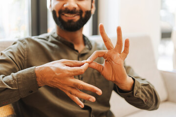 Smiling man using sign language communicating, selective focus on hands