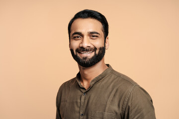 Fototapeta premium Portrait of positive, handsome indian man smiling and posing isolated on beige background