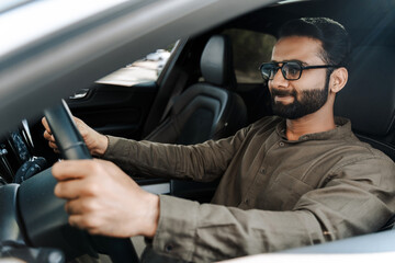 Handsome middle aged businessman wearing sunglasses driving modern car. Insurance concept