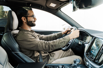 Happy Indian businessman driving modern car in the city