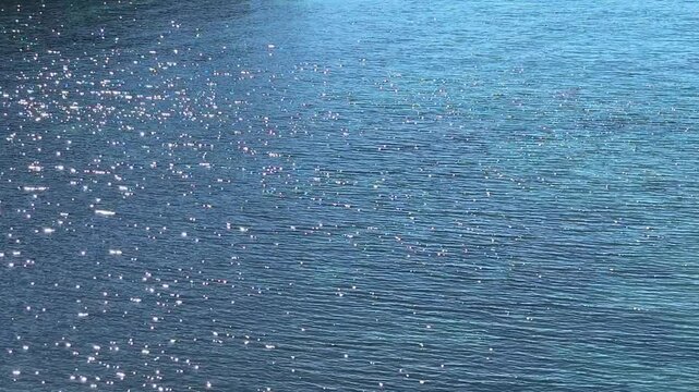 Blue shiny water surface with sun reflections.