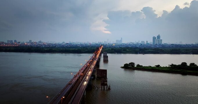 Long Bien bridge traffic with Hanoi city skylines in background at sunset, Panoramic drone shot