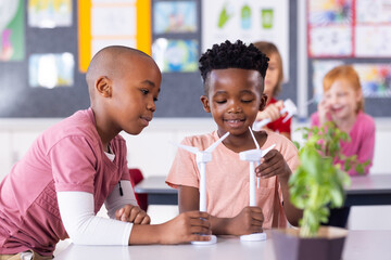 In school, diverse children studying wind turbines and renewable energy in classroom