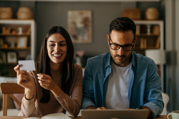 Young cheerful couple shopping online at home. Couple shopping online with credit card and laptop.