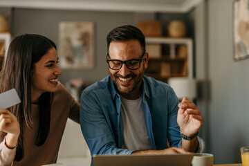 The couple enjoys shopping online or booking vacation tickets together, sitting in their cozy home