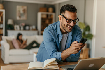 Portrait of a handsome Caucasian man looking at smartphone, working online from his home