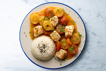 White fish stew with leeks and cherry tomatoes served with rice. Top view table with  decoration.