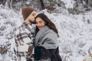 Portrait of a young happy and loving couple having fun in a snowy forest