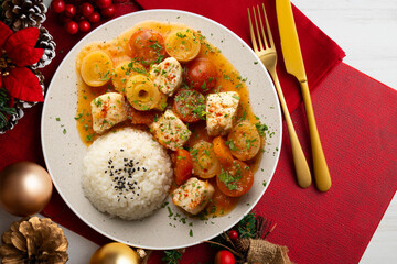 White fish stew with leeks and cherry tomatoes served with rice. Top view table with Christmas decoration.