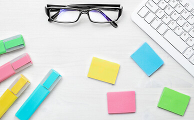bright markers and stickers are on the table next to the glasses and keyboard