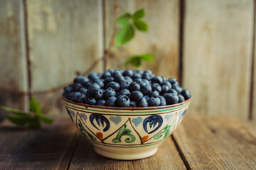 Blueberries in ceramic bowl on rustic wooden background. Selective focus. Shallow depth of field.