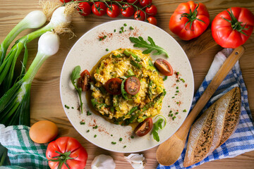 Scrambled organic chicken eggs with green asparagus and tomato. Top view table with  decoration.