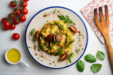 Scrambled organic chicken eggs with green asparagus and tomato. Top view table with  decoration.
