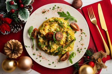 Scrambled organic chicken eggs with green asparagus and tomato. Top view table with Christmas decoration.
