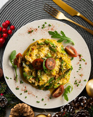 Scrambled organic chicken eggs with green asparagus and tomato. Top view table with Christmas decoration.