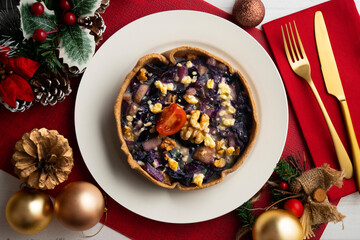 Individual vegan quiche with vegetables and red cabbage. Top view table with christmas decoration.