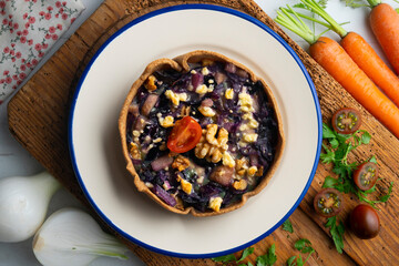 Individual vegan quiche with vegetables and red cabbage. Top view table with  decoration.