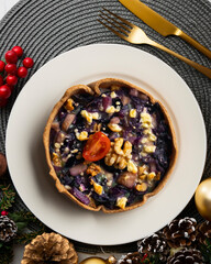 Individual vegan quiche with vegetables and red cabbage. Top view table with christmas decoration.