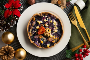 Individual vegan quiche with vegetables and red cabbage. Top view table with christmas decoration.