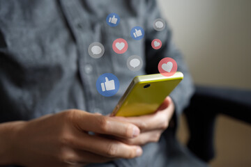 スマートフォンでSNSアプリを見ている人の手。いいね、お気に入り、コメントのアイコンが表示されている。ソーシャルメディアやコミュニケーションに関する概念的なイメージ。