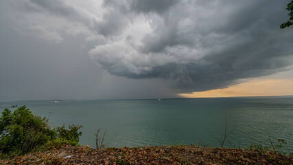 View from Land of clouds shifting from Sun to Rain over sea with sunset in the back in Australia -...