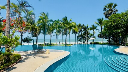 Pool view with Palm trees in the back under a clear blue sky in Hua Hin Thailand - concept of Travel, holiday, rest, tropic