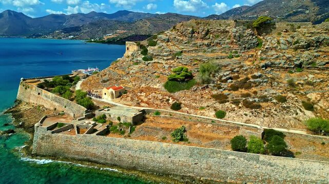 Aerial ascend and pullback of Spinalonga Fortress, Crete, Greece, highlighting its ancient walls and the Mediterranean landscape