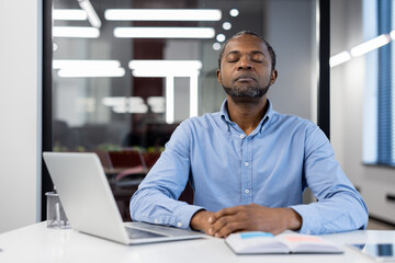 Business professional practicing mindfulness meditation at desk, eyes closed, achieving peace and...