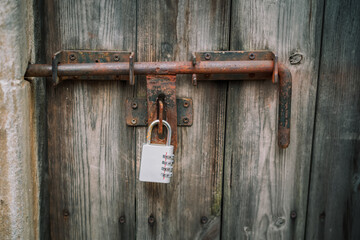Old wooden door with vintage metal sliding door bolt with Combination Padlock