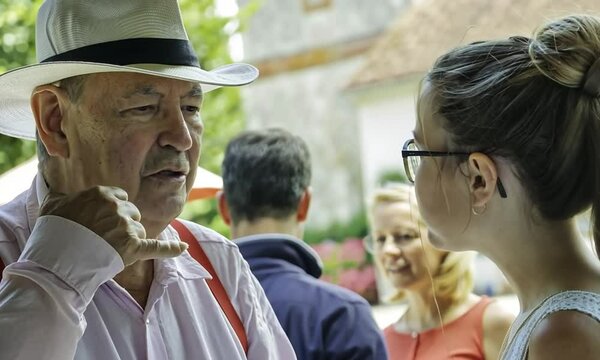 Grand-p&egrave;re mimant un appel t&eacute;l&eacute;phonique &agrave; sa petite-fille, utilisant ses doigts pour former un t&eacute;l&eacute;phone, avec sa bouche bougeant pour imiter la conversation
