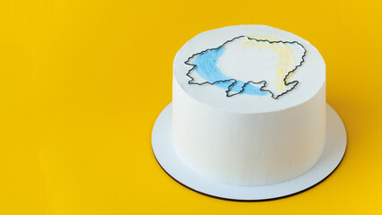 Cake with white cream cheese frosting decorated with Ukrainian border silhouette drawing. Anniversary cake for an independence Day of Ukraine on the yellow background.