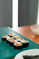 Freshly made sushi rolls with colorful vegetables sitting on a green cutting board