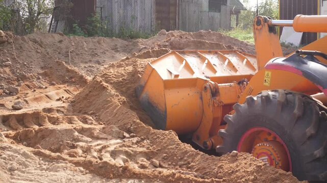 A bulldozer picks up sand at a construction site
