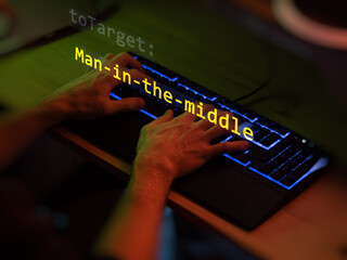 Cyber attack man-in-the-middle text in foreground screen, hands of a anonymous hacker on a led keyboard. Vulnerability text in informatic system style, code on editor screen. Text in English.