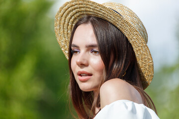 Portrait of a brunette girl in a straw hat in nature. Close-up