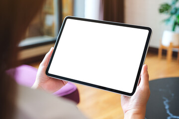 Mockup image of a woman holding digital tablet with blank desktop screen at home
