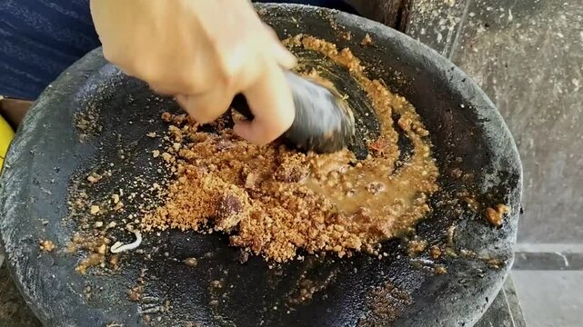 Close Up Shoot Traditional chili sauce of Indonesia made by hand grinding chilies and peanut sauce on pestle stone mortar. Peanut Sauce or Sambal Pecel.
